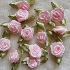 several pink roses with green leaves on a white surface and some are made out of fabric