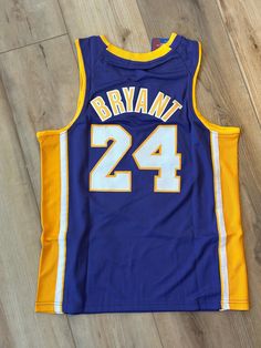 a blue and yellow basketball jersey with the number 24 on it, sitting on a wooden floor