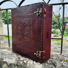 an old book is sitting on top of a stone wall in front of a wrought iron fence