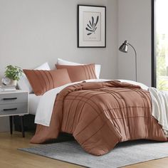 a bed in a bedroom with orange and white comforter on top of the bed