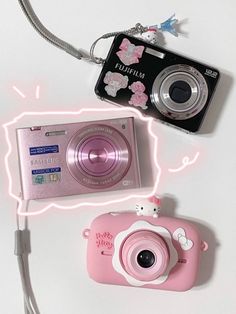 a pink camera sitting on top of a white table next to a keychain