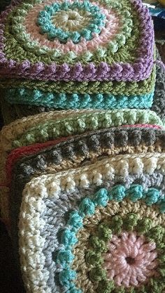 four crocheted grannys are stacked on top of each other in different colors