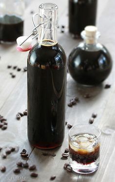 there is a bottle with some liquid in it and coffee beans on the table next to it