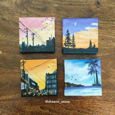 four small paintings are sitting on a wooden table with wires and telephone poles in the background