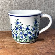 a blue and white coffee cup sitting on top of a wooden table next to a wall