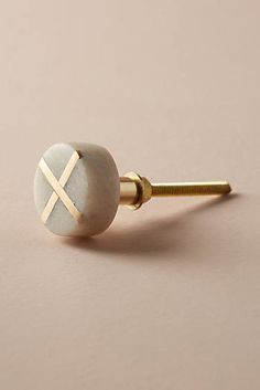 a pair of gold and white earrings on a pink surface with a small round stone in the middle