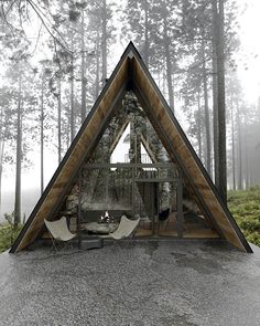 a house in the middle of a forest with two chairs and a table inside it