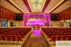 an event hall with rows of red chairs and purple uplighting on the ceiling