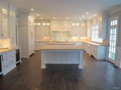 a large kitchen with white cabinets and wood floors