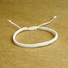 a white string bracelet on a brown surface