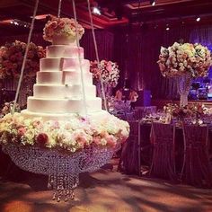 a large wedding cake sitting on top of a table next to tall vases filled with flowers