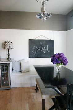 a black table topped with purple flowers next to a wall mounted chalkboard that says happy