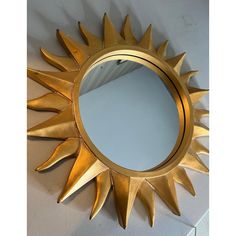 a gold sun shaped mirror sitting on top of a white counter next to a wall