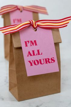 two brown paper bags with pink and red tags on them that say i'm all yours