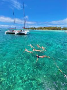 two people are swimming in the clear blue water next to a sailboat on an island