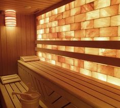 a wooden bench sitting next to a wall with lights on it's sides and two mugs in front of the bench