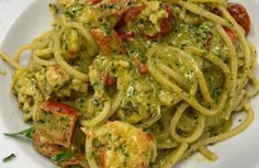 a white plate topped with pasta covered in pesto