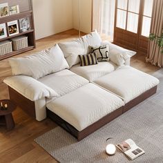 a large white couch sitting on top of a wooden floor next to a book shelf