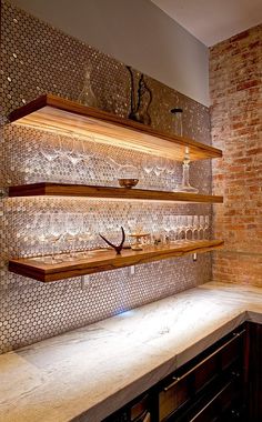 a kitchen counter with wine glasses on it and a brick wall in the back ground