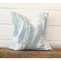 a blue and white pillow sitting on top of a wooden bench next to a wall