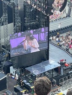 a large crowd is watching a concert on the big screen