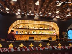 a man sitting at a bar with lots of bottles on the shelves and lights above it