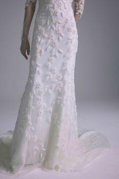 a woman in a white wedding dress with flowers on the bouncy skirt and sleeves