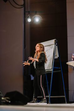 a woman standing in front of a projector screen with her hands out to the side