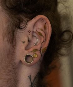 a man with piercings on his ears and behind the ear is a flower tattoo