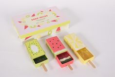 three popsicles with different designs in a box on a white surface next to each other