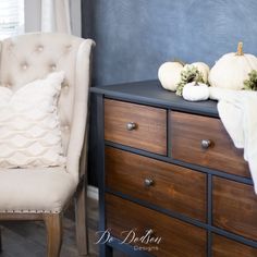 a white chair sitting in front of a dresser with pumpkins on top of it