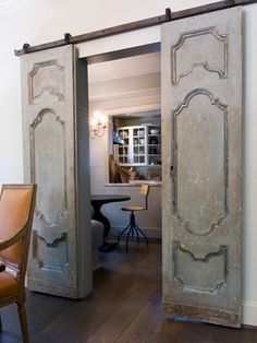 an open door in the middle of a room with a table and chairs behind it