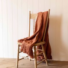 a chair with a blanket on top of it next to a wooden floor and wall