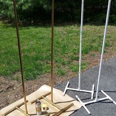 three metal poles on top of a wooden board in the middle of some grass and dirt