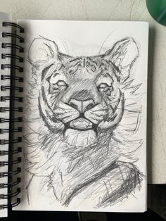 a pencil drawing of a tiger's face on top of a notepad next to a pen