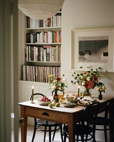 a dining room table is set for two with candles and flowers in vases on it