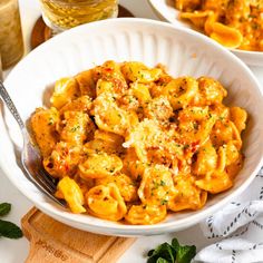 two bowls filled with pasta and sauce on top of a table