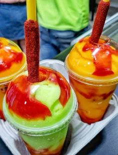 three different colored drinks in plastic cups with straws sticking out of the top one