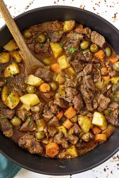 beef stew with potatoes and carrots in a skillet on a white tablecloth