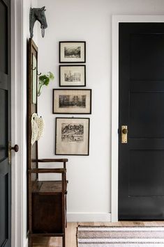 an entryway with black doors and pictures on the wall