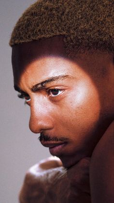 a close up of a person wearing a hat and holding a cell phone to his ear