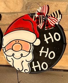 a sign with santa clause on it is next to a brick wall that says ho ho hoo