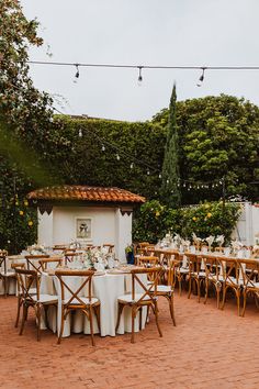 an outdoor dining area with tables and chairs set up for a formal dinner in the garden