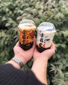 someone holding two small jars with food in it's hands, one is filled with liquid and the other has chinese writing on them