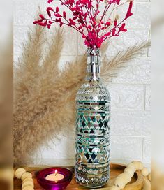 a glass vase with flowers in it sitting on a table next to a candle and beads