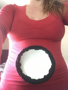 a pregnant woman wearing a red shirt and holding a white plate in the shape of a circle