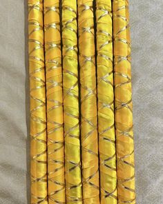 several yellow candles are lined up on a white tablecloth with silver trimmings