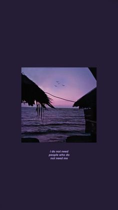 the sky is purple and there are two thatched umbrellas in front of the ocean