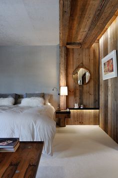 a bedroom with wood paneling and white bedding, along with a mirror on the wall