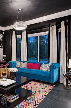 a living room with black walls and blue couches